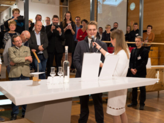 Daniel Graßmugg erklärt Dr. Sandra Ohms vom ORF und dem Publikum sein Spirituosen-Präsentationsmöbel &quot;spining spirits&quot;